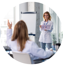 A women holding a tablet with medical information displayed, teaching a class.