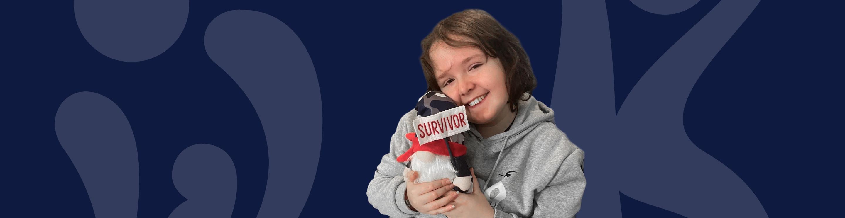 IWK patient Jeric holding a stuffed animal with a "survivor" banner.