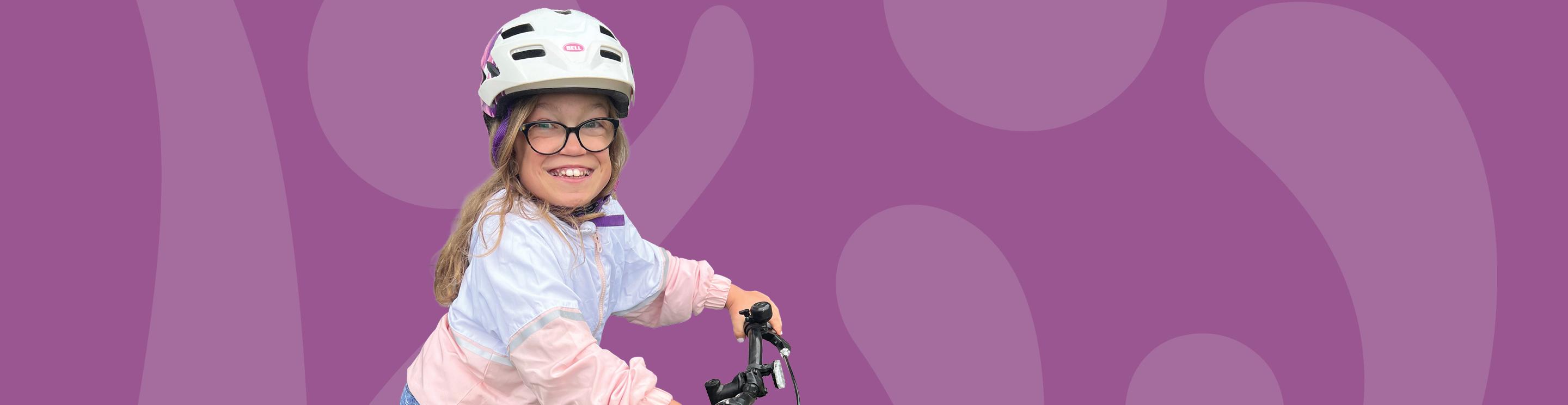 Kamie wearing a white bike helmet and glasses while riding a bicycle.