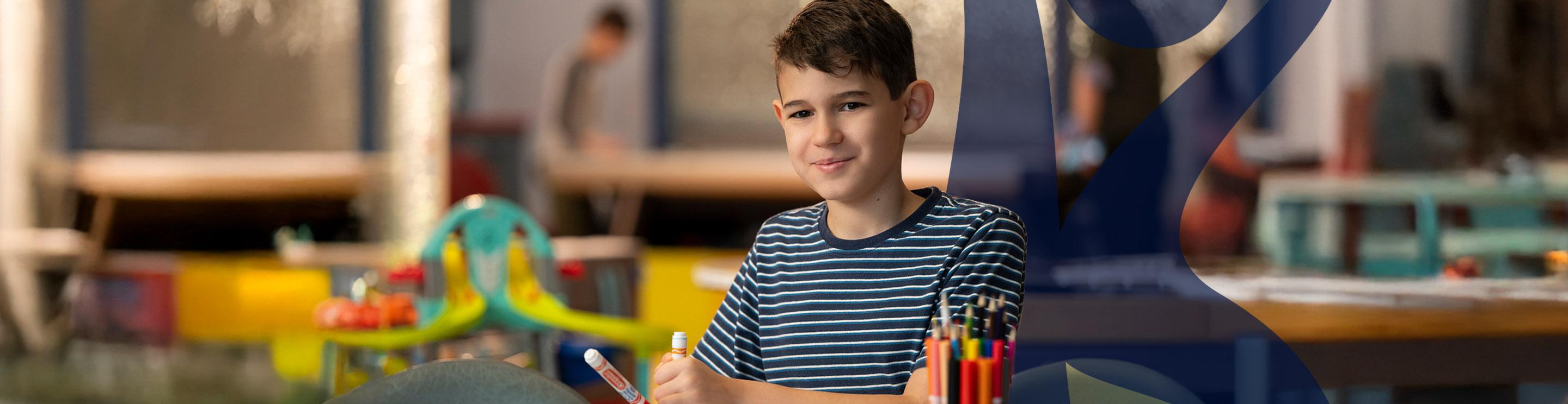 Jannie, an IWK patient, colouring at a table and smiling