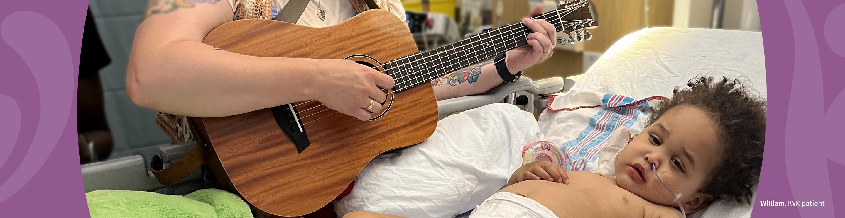 William, IWK patient, listening to a music therapist playing the guitar.