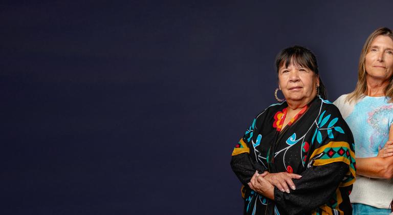 Three women standing shoulder to shoulder with a dark blue background