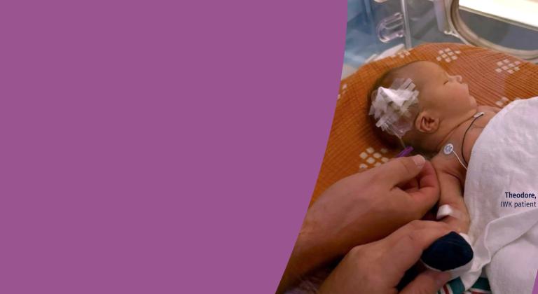 Caregiver gently holding hand of Theodore receiving care in an IWK incubator