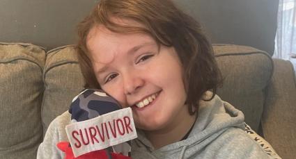 IWK patient, Jeric, holding a stuffed toy with a "survivor" banner.