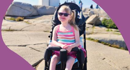 Lyla smiling at the camera with a lighthouse in the background.