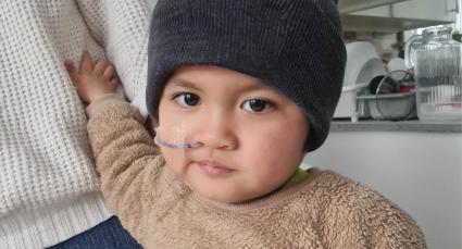 Johnny receiving hospital care, alongside a close-up with a nasal tube holding an adult’s hand.