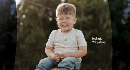Beckett sitting outdoors in a wooded setting, smiling with his eyes closed and hands clasped in front of him. Text reads “Beckett, IWK patient.”