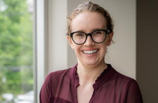 Maggie, an IWK patient, wearing glasses and smiling at the camera.