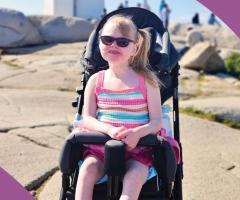Lyla smiling at the camera with a lighthouse in the background.