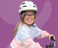 Kamie wearing a white bike helmet and glasses while riding a bicycle.